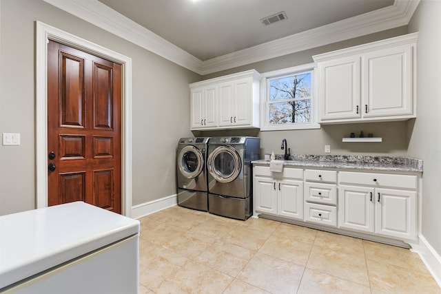 clothes washing area featuring cabinets, sink, crown molding, light tile patterned floors, and washing machine and clothes dryer