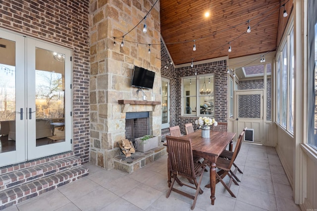 sunroom with french doors, an outdoor stone fireplace, an inviting chandelier, wooden ceiling, and lofted ceiling