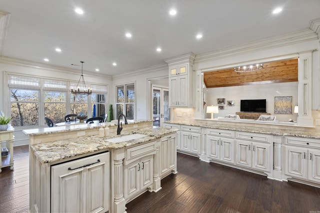 kitchen featuring light stone countertops, sink, hanging light fixtures, dark hardwood / wood-style flooring, and an island with sink