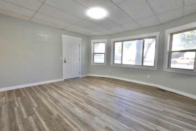 empty room featuring a drop ceiling and light hardwood / wood-style floors