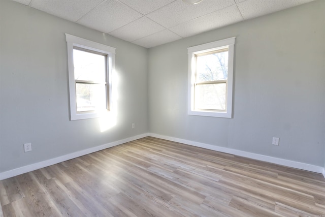 empty room featuring light wood-type flooring and a paneled ceiling