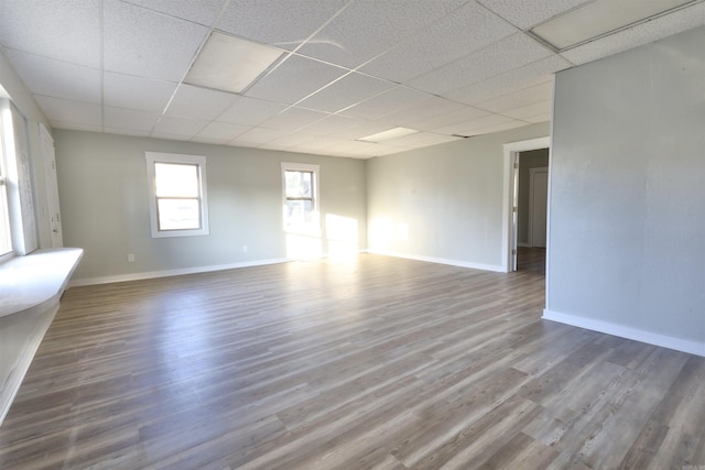 unfurnished room with hardwood / wood-style floors and a drop ceiling