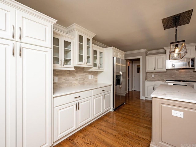 kitchen with white cabinets, dark hardwood / wood-style floors, ornamental molding, appliances with stainless steel finishes, and decorative light fixtures