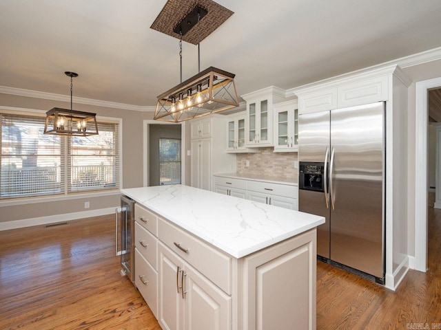 kitchen featuring built in fridge, a center island, white cabinetry, and ornamental molding