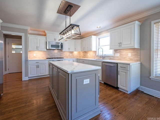 kitchen featuring hanging light fixtures, white cabinets, stainless steel appliances, and sink