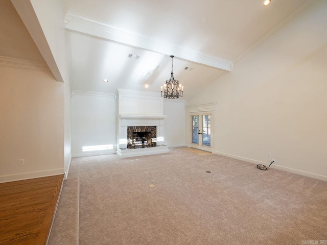 unfurnished living room featuring carpet flooring, beam ceiling, a fireplace, and french doors