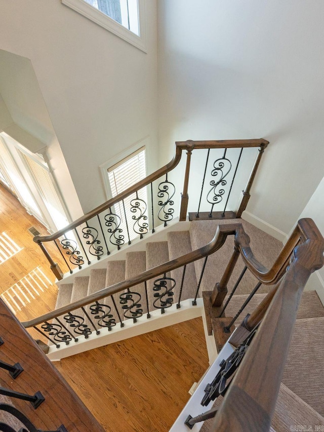 stairway with a towering ceiling, hardwood / wood-style flooring, and plenty of natural light