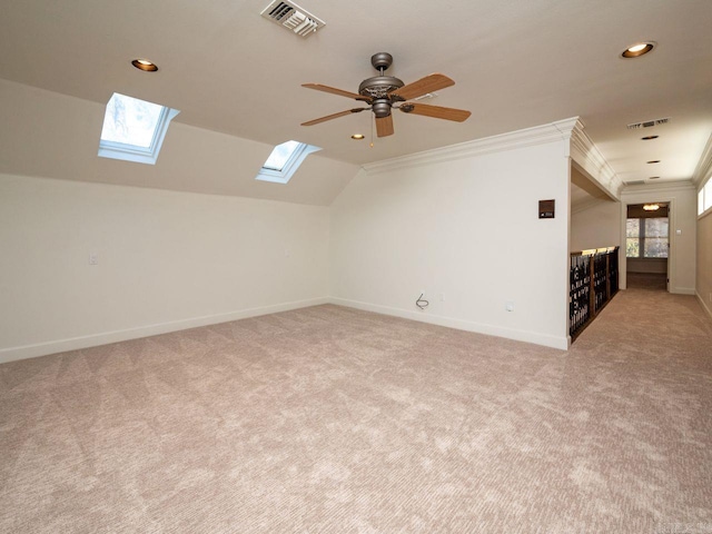 additional living space featuring ceiling fan, light colored carpet, and lofted ceiling with skylight