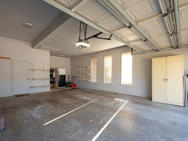 garage with stainless steel fridge and a garage door opener