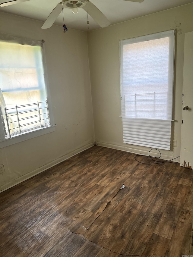 unfurnished room featuring plenty of natural light, ceiling fan, and dark wood-type flooring