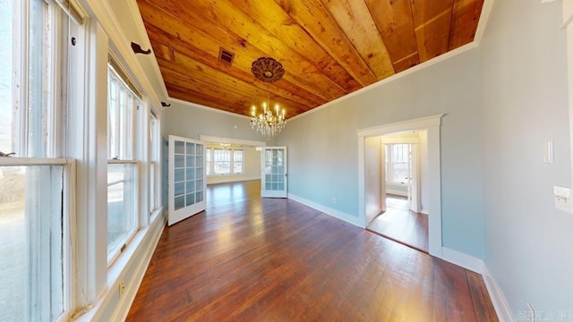 spare room featuring french doors, an inviting chandelier, dark hardwood / wood-style floors, ornamental molding, and wood ceiling