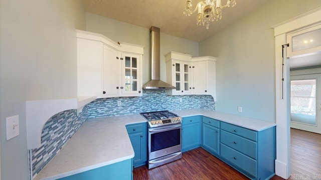 kitchen with an inviting chandelier, white cabinets, stainless steel gas range, wall chimney exhaust hood, and decorative backsplash