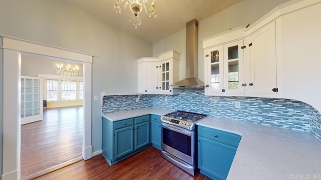 kitchen with gas stove, wall chimney range hood, blue cabinets, a notable chandelier, and white cabinets