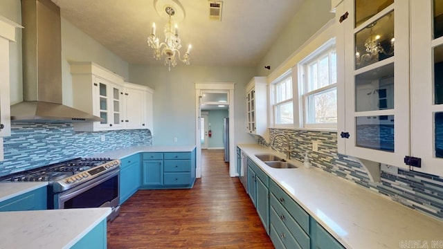 kitchen with white cabinets, sink, wall chimney exhaust hood, decorative light fixtures, and stainless steel range oven