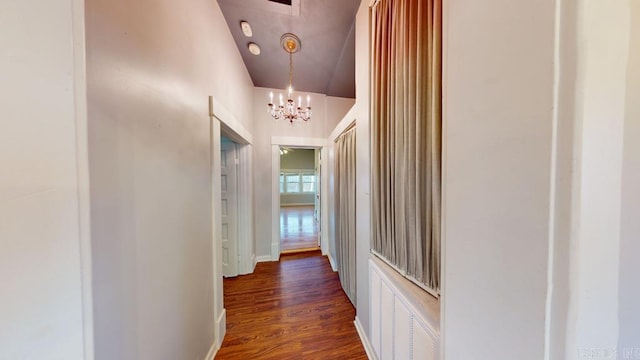 hallway with dark wood-type flooring and a notable chandelier