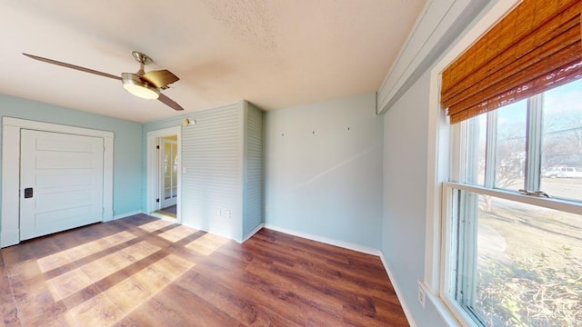 unfurnished bedroom featuring multiple windows, ceiling fan, a closet, and dark wood-type flooring