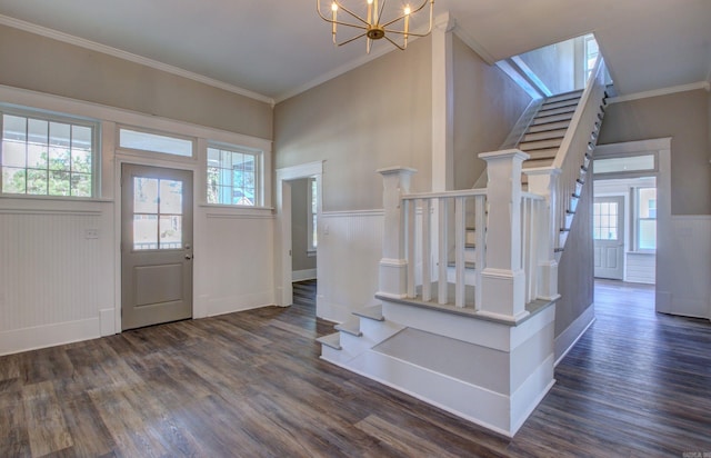 entrance foyer featuring plenty of natural light, ornamental molding, dark wood-type flooring, and an inviting chandelier