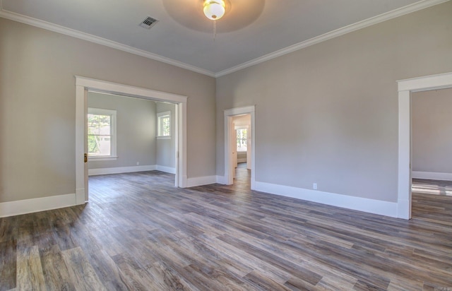 empty room with plenty of natural light, dark hardwood / wood-style flooring, and ornamental molding