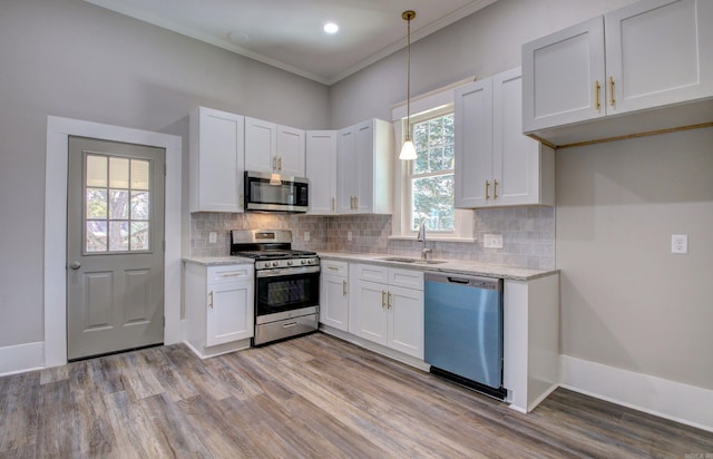 kitchen with pendant lighting, stainless steel appliances, white cabinetry, and crown molding