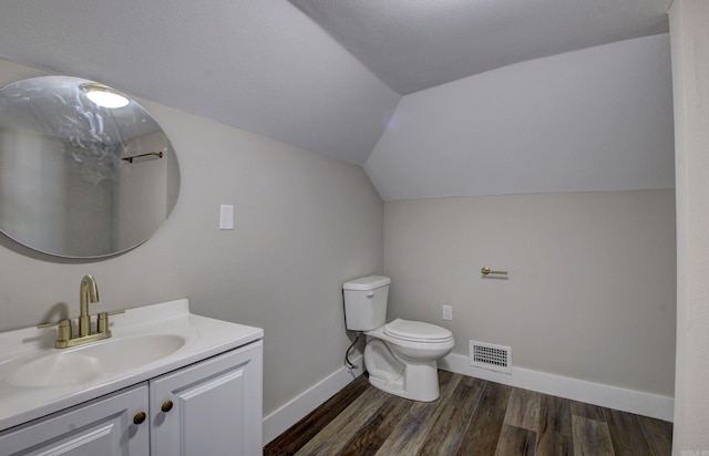 bathroom with wood-type flooring, vanity, toilet, and lofted ceiling