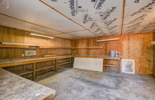 basement with an AC wall unit, a workshop area, and wooden walls