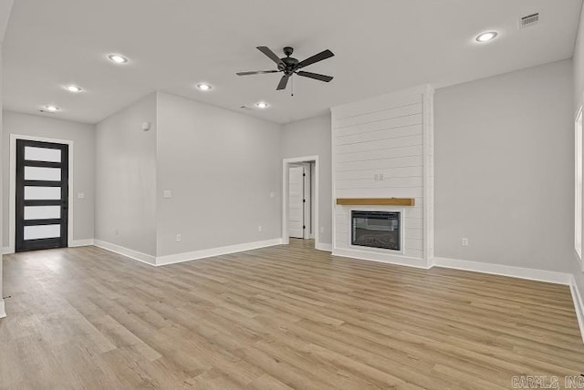 unfurnished living room featuring ceiling fan, a fireplace, and light hardwood / wood-style flooring