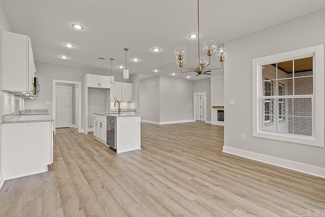 kitchen featuring stainless steel dishwasher, sink, decorative light fixtures, a chandelier, and white cabinetry