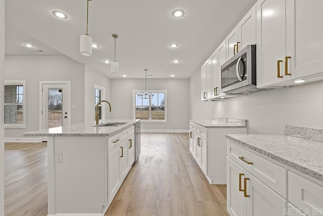 kitchen with pendant lighting, sink, white cabinetry, and a kitchen island with sink