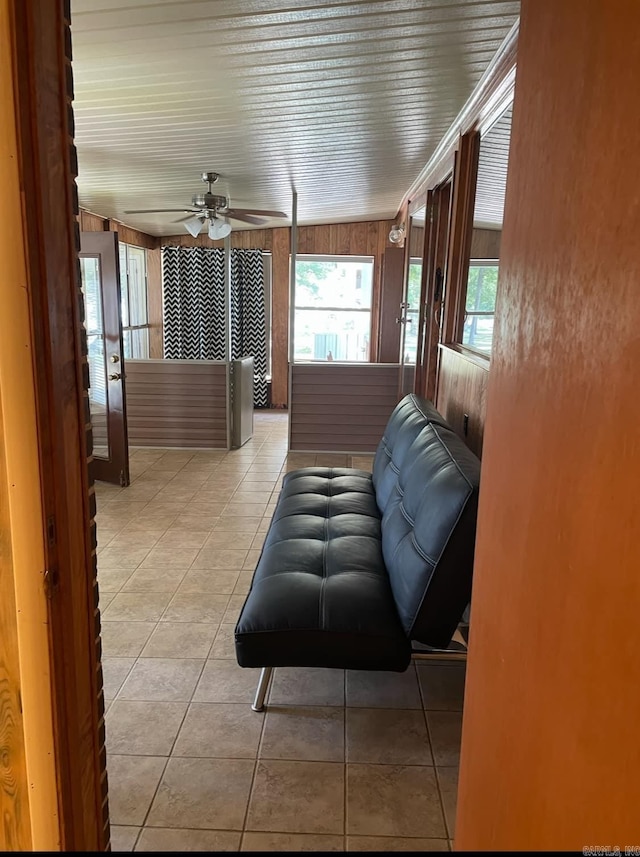 tiled living room featuring wood walls and ceiling fan