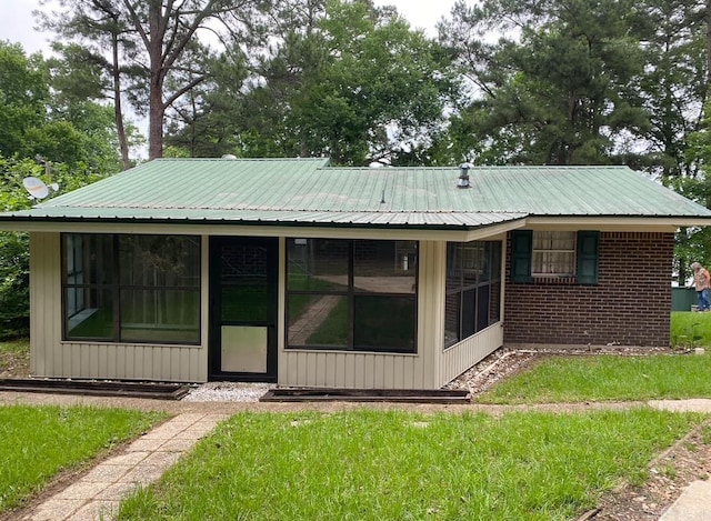 rear view of house featuring a sunroom and a yard