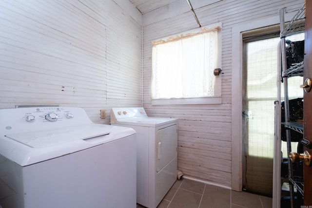 laundry room featuring dark tile patterned flooring, washer and clothes dryer, and wooden walls