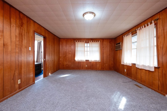 carpeted spare room featuring a wall mounted air conditioner and wood walls