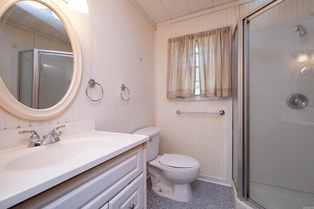 bathroom with vanity, toilet, a shower with door, and wood walls