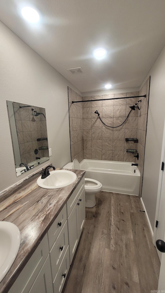 full bathroom with hardwood / wood-style floors, vanity, toilet, and tiled shower / bath combo