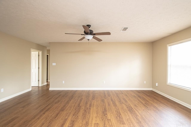 spare room with plenty of natural light, ceiling fan, dark hardwood / wood-style flooring, and a textured ceiling