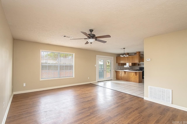 unfurnished living room featuring a textured ceiling, light hardwood / wood-style floors, and a wealth of natural light