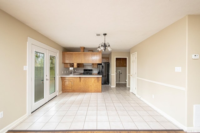 kitchen featuring french doors, hanging light fixtures, an inviting chandelier, kitchen peninsula, and black appliances