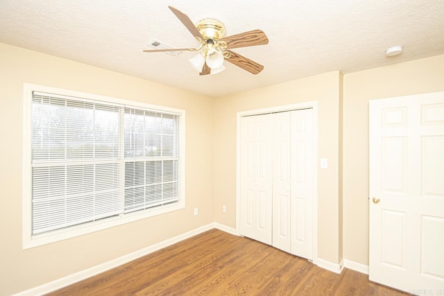 unfurnished bedroom with hardwood / wood-style floors, ceiling fan, a textured ceiling, and a closet