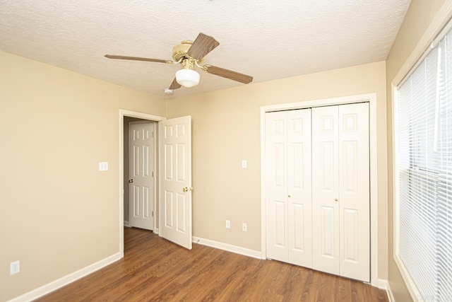 unfurnished bedroom featuring ceiling fan, dark hardwood / wood-style flooring, a textured ceiling, and a closet