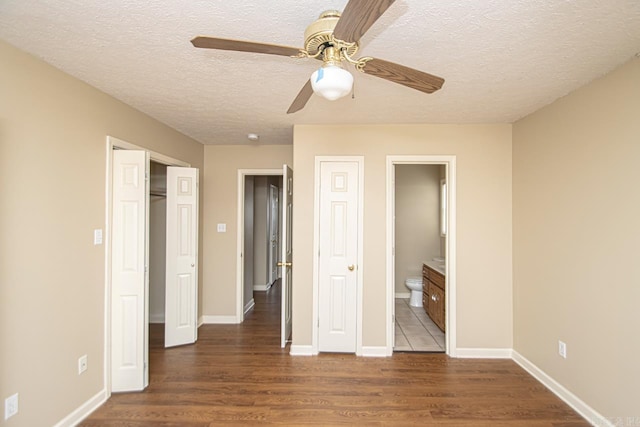 unfurnished bedroom featuring a textured ceiling, dark hardwood / wood-style flooring, ensuite bath, and ceiling fan