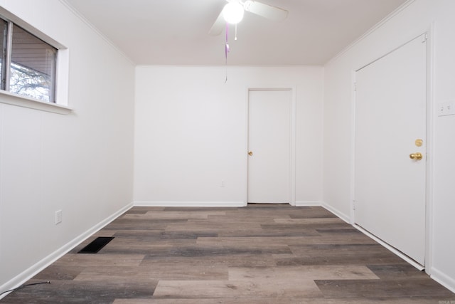 empty room with ceiling fan, dark hardwood / wood-style flooring, and ornamental molding