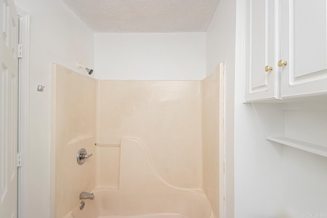 bathroom featuring  shower combination and a textured ceiling