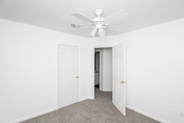 carpeted spare room featuring a textured ceiling and ceiling fan