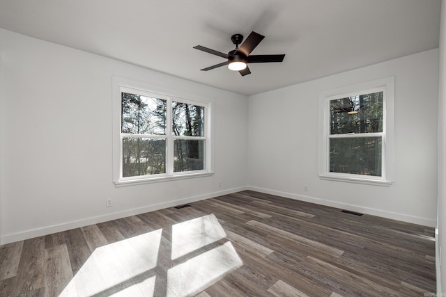 spare room with ceiling fan, dark wood-type flooring, and a wealth of natural light