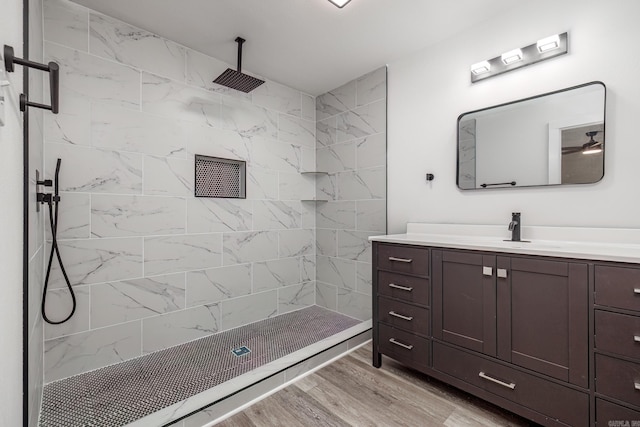 bathroom with tiled shower, vanity, and hardwood / wood-style flooring