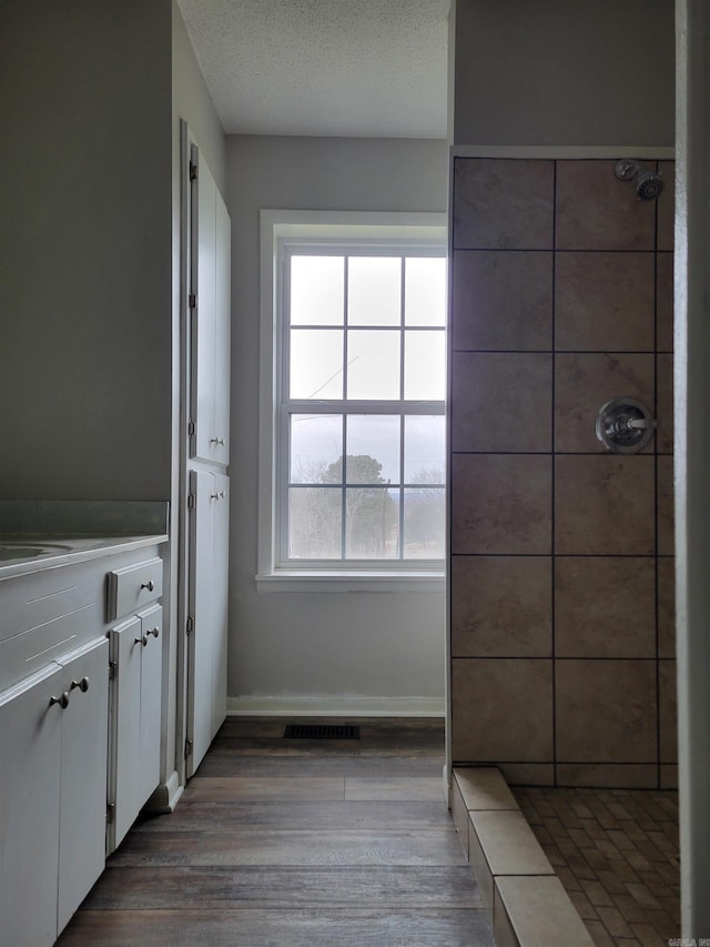 bathroom with hardwood / wood-style floors, vanity, a textured ceiling, and walk in shower