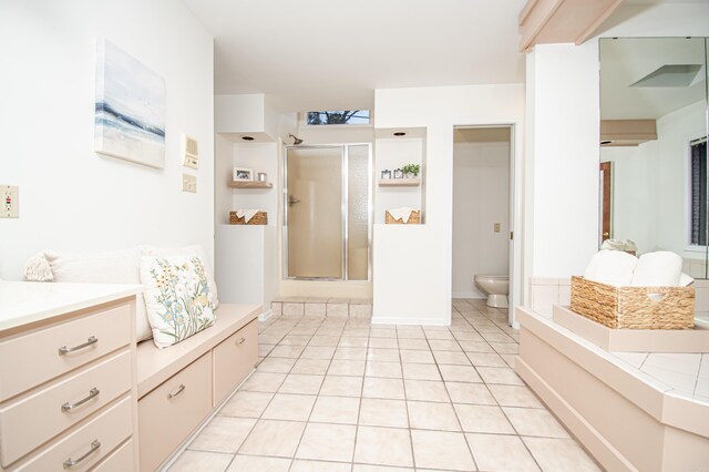 bathroom featuring tile patterned flooring, vanity, toilet, and a shower with shower door