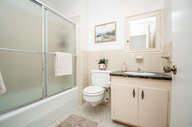 full bathroom featuring tile patterned floors, bath / shower combo with glass door, toilet, vanity, and tile walls