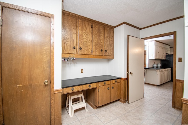 kitchen with wood walls, built in desk, a textured ceiling, and ornamental molding