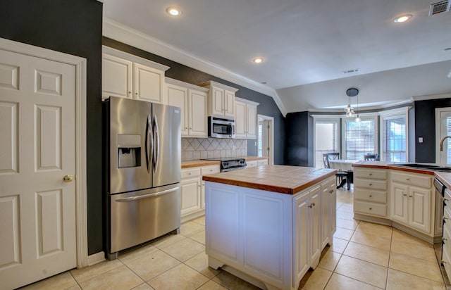 kitchen with tile countertops, lofted ceiling, appliances with stainless steel finishes, tasteful backsplash, and a kitchen island